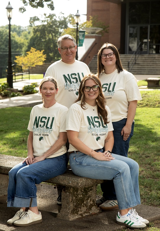 4 peoplw wearing cream nsu shirts in front of a building