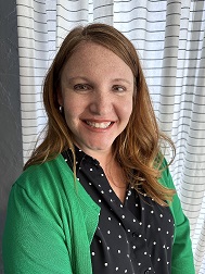 Image of a woman with red hear and a green sweater. 